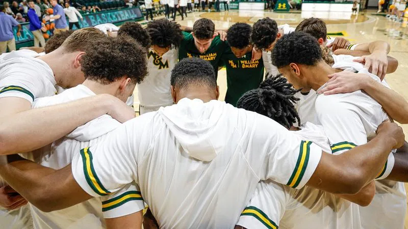 The William & Mary men's basketball team huddles up with arms on shoulders prior to the season opener against Georgian Court in 2025.