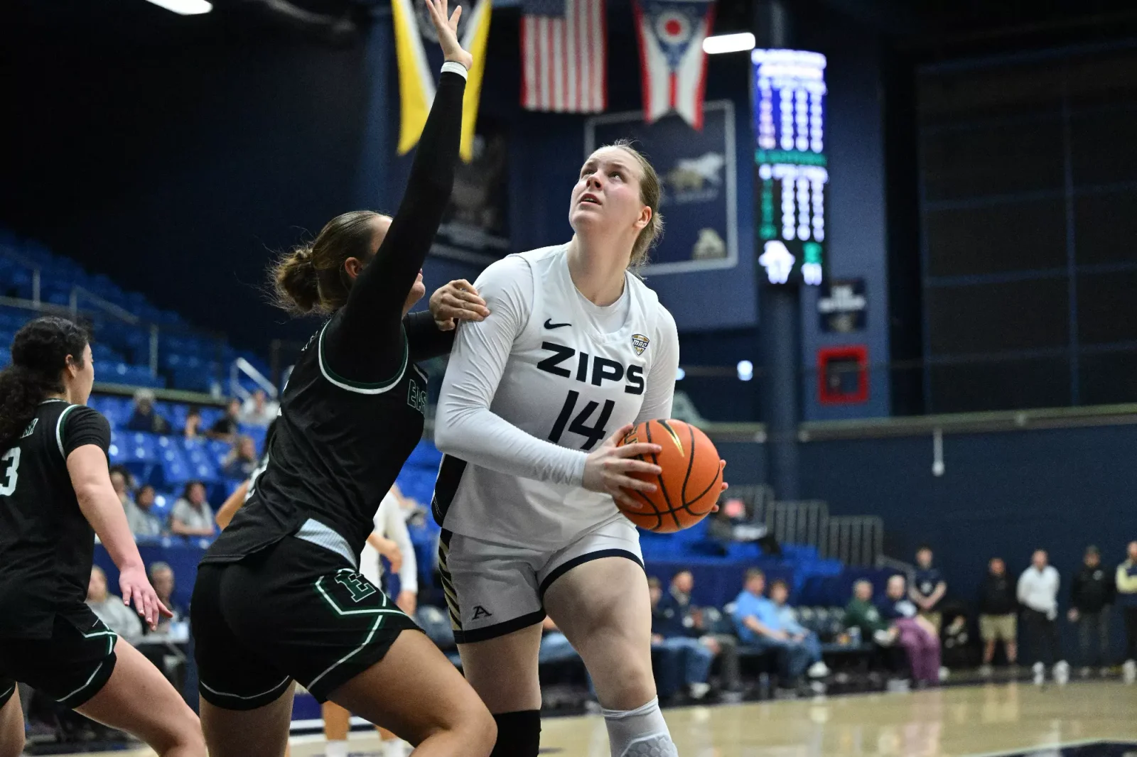 An Akron women's basketball player prepares to shoot against Eastern Michigan in a white Zips uniform