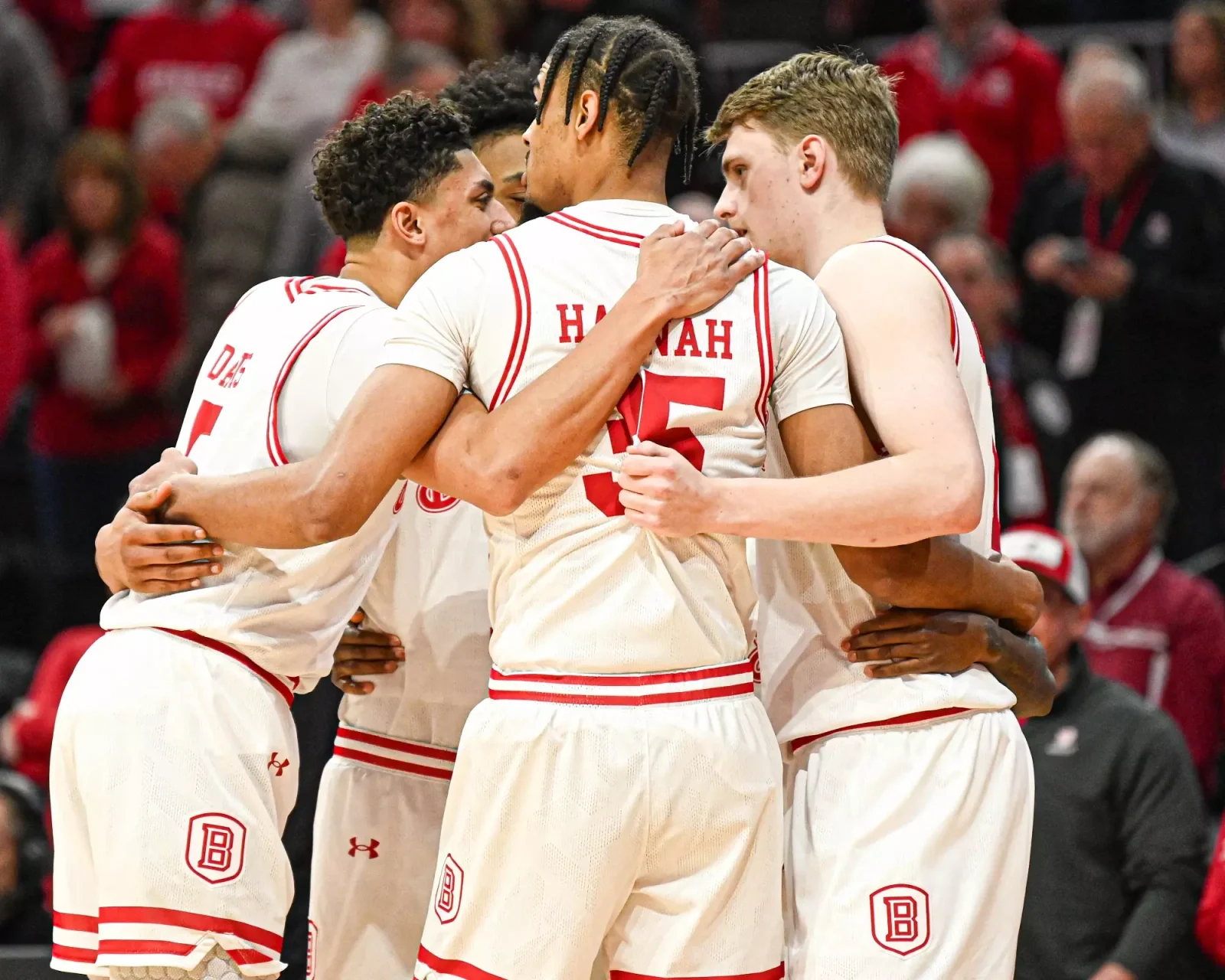 Bradley men's basketball players huddle in white Braves uniforms on their home court