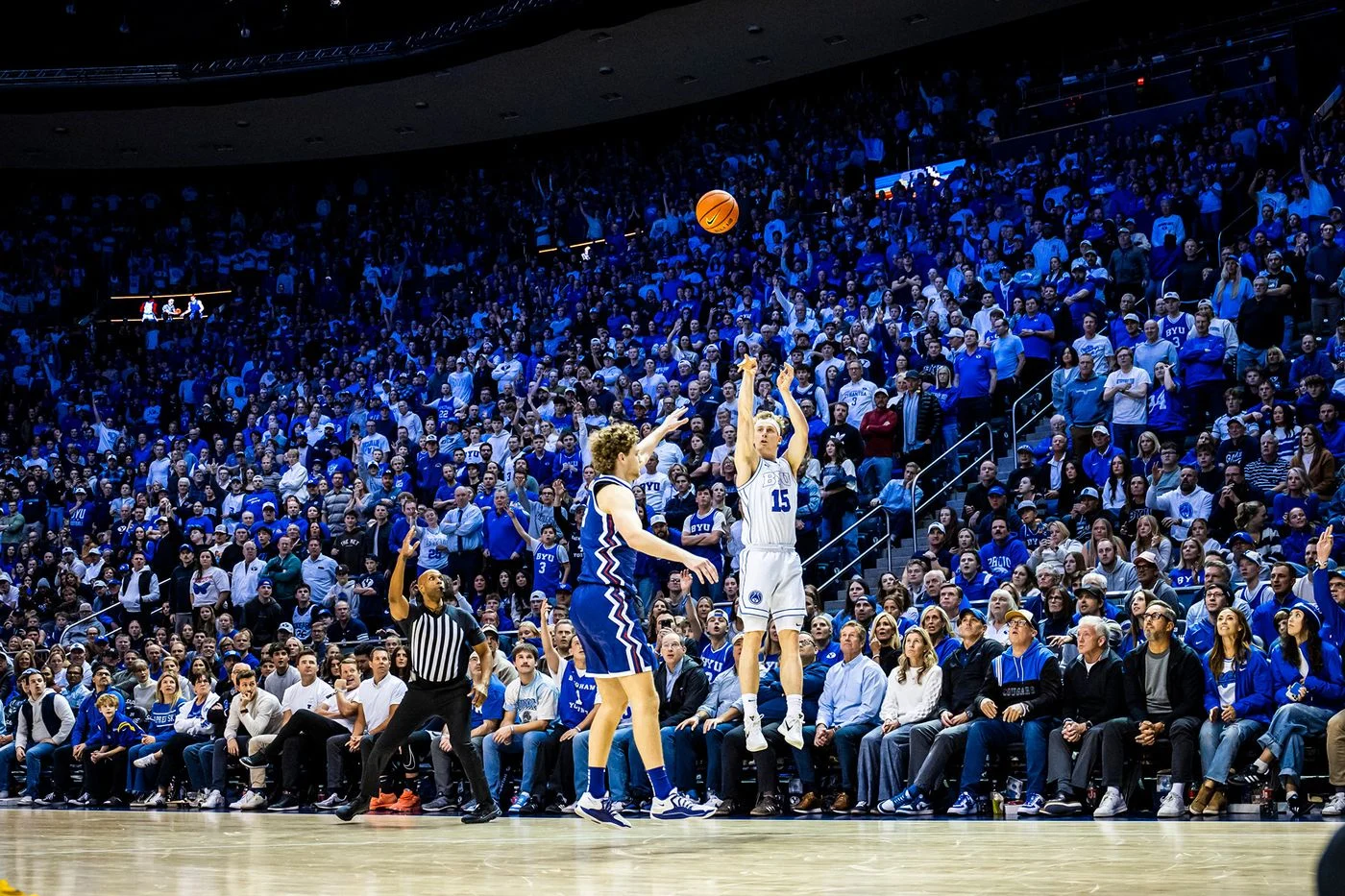 A BYU men's basketball player shoots in front of a packed Marriott Center crowd