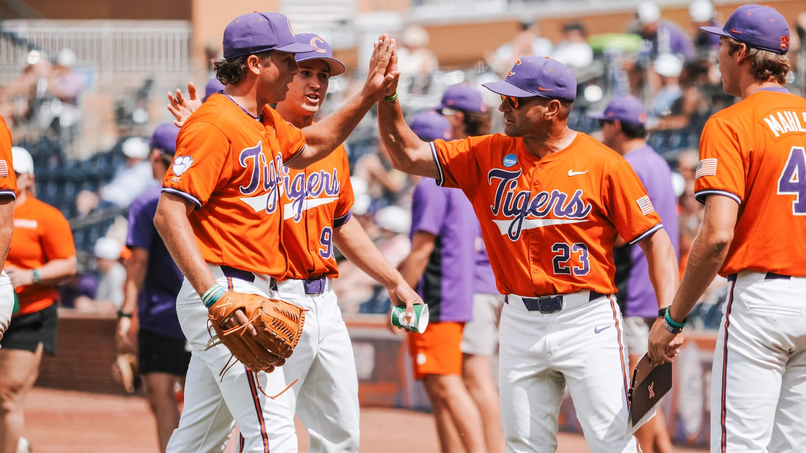 Clemson baseball coach Erik Bakich high-fives a Tigers player in an orange uniform