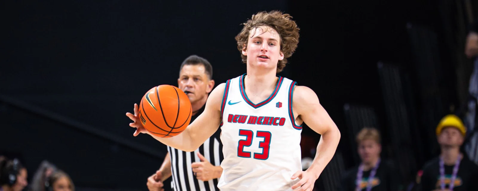 New Mexico men’s basketball player dribbles in a white Lobos uniform