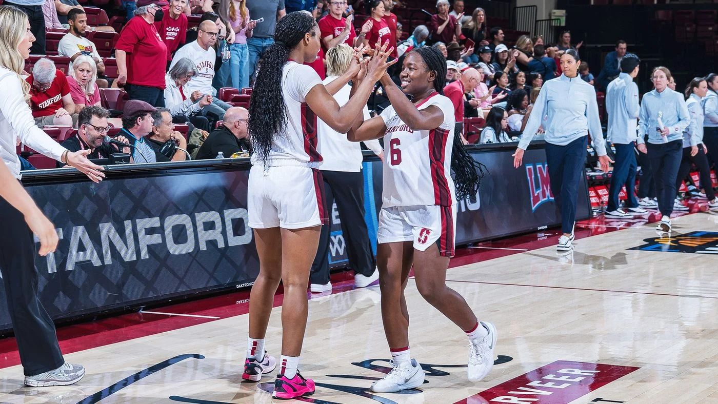 Stanford women's basketball players high-five in Cardinal uniforms at Maples Pavilion